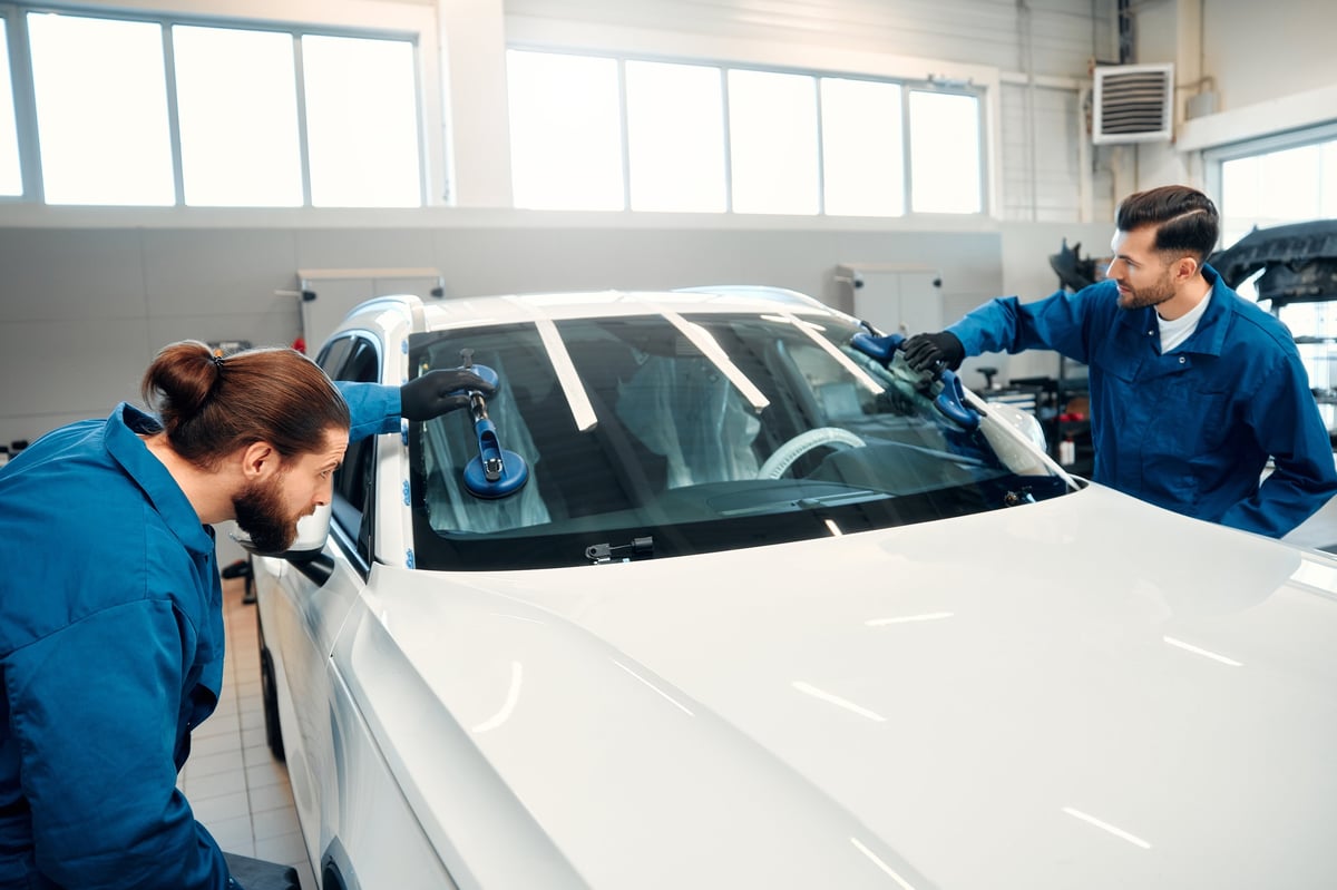 Technician replacing a windscreen on a vehicle